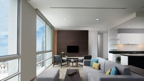 Un salon moderne avec un canapé gris, une table basse et un téléviseur à écran plat fixé au mur.