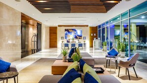 Eine moderne Lobby mit Empfangstresen, einer Sitzecke und großen Fenstern.