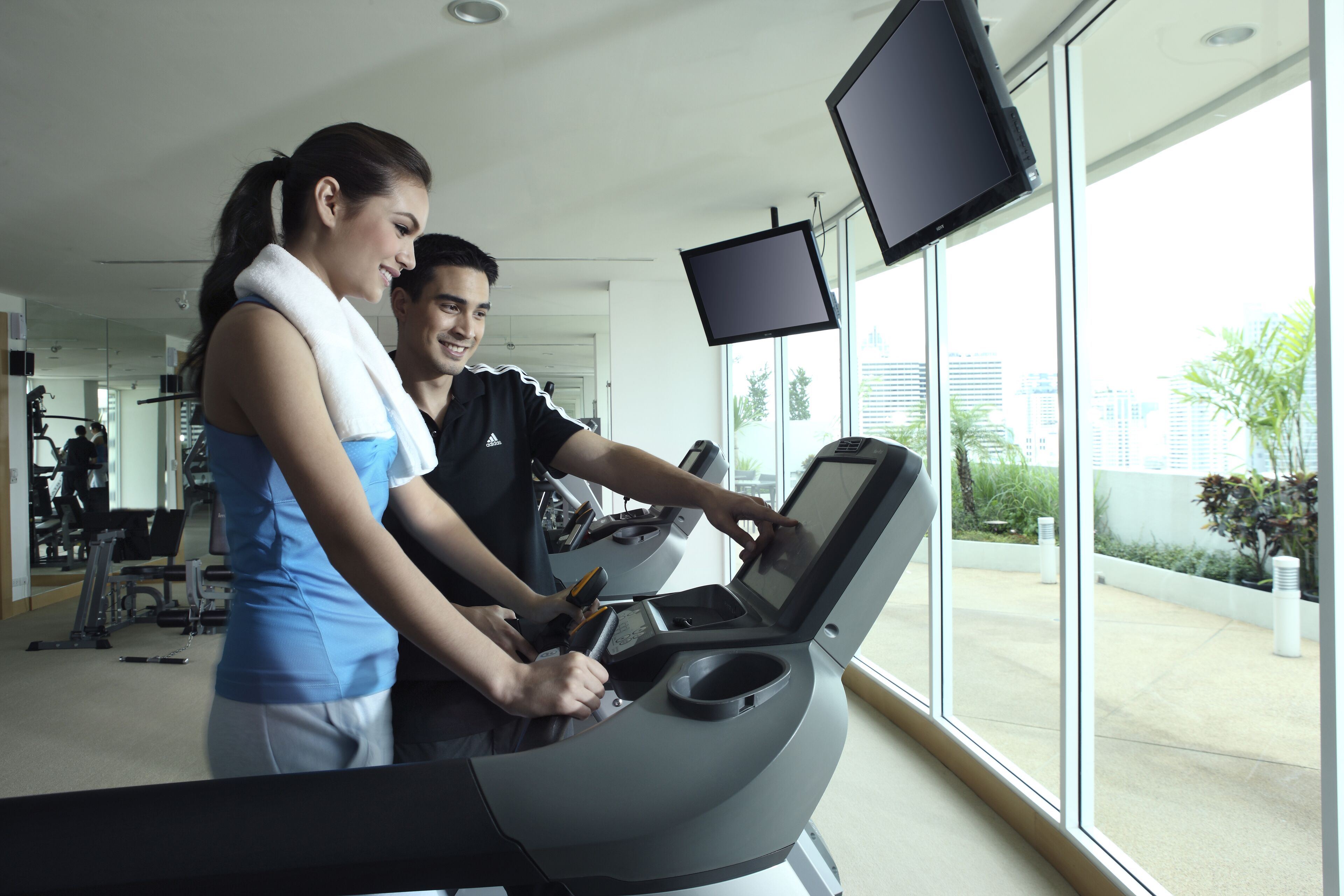 Un gimnasio con cinta de correr, un ventanal grande y una pantalla de televisión.