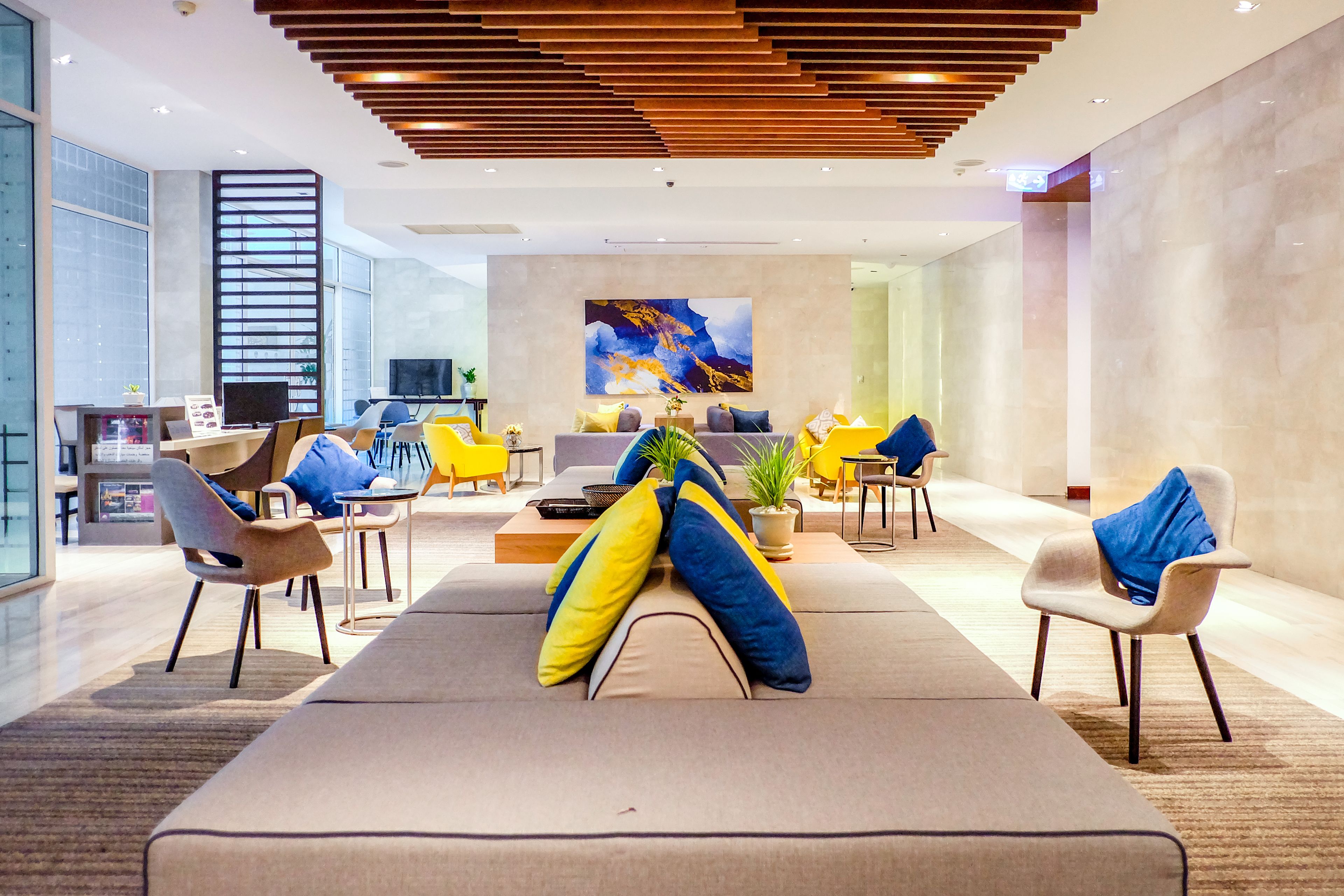 A modern lobby with a large sofa, chairs, and a TV.