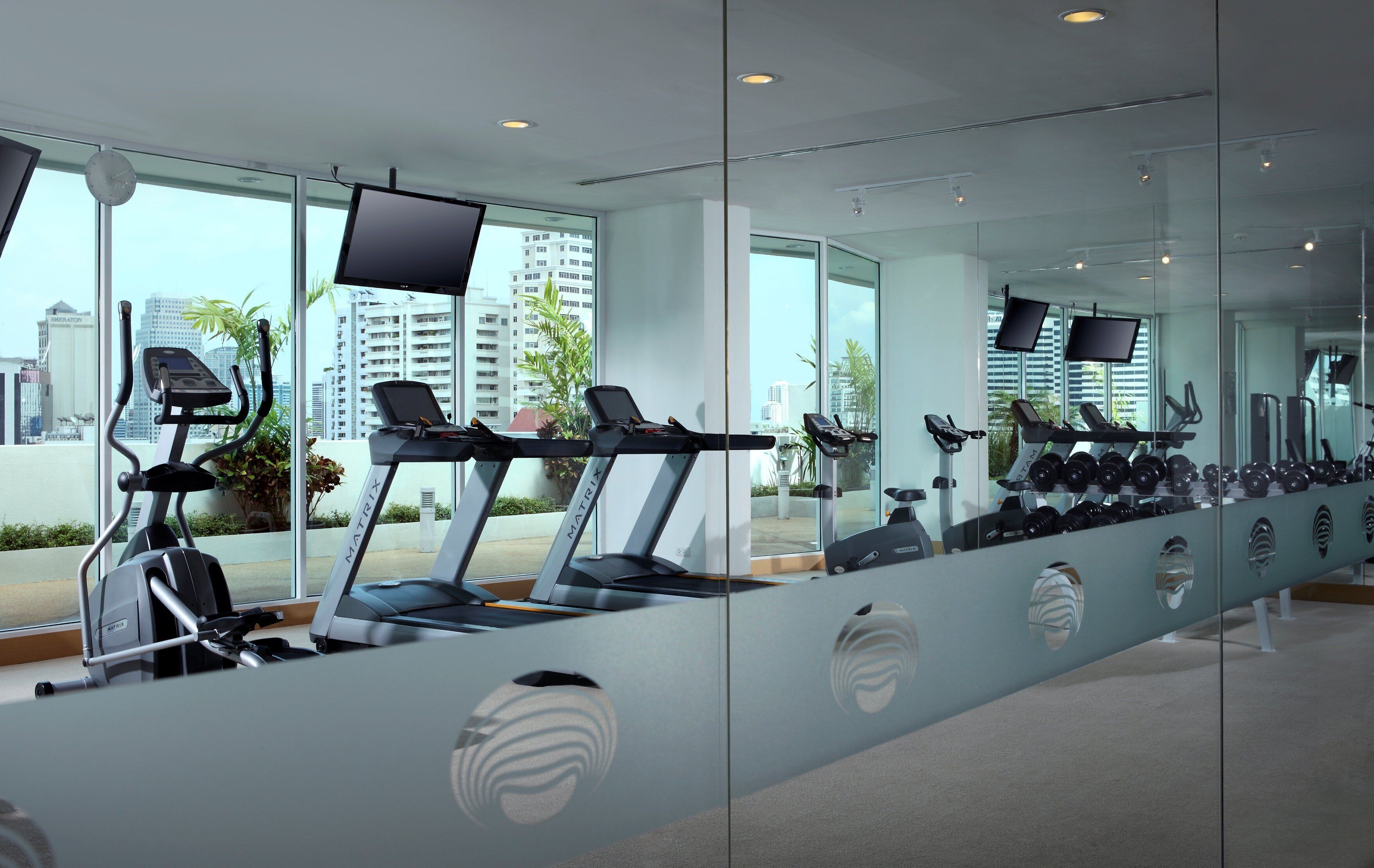 Une salle de sport moderne équipée de tapis de course, de vélos d’appartement et d’appareils d’exercice.