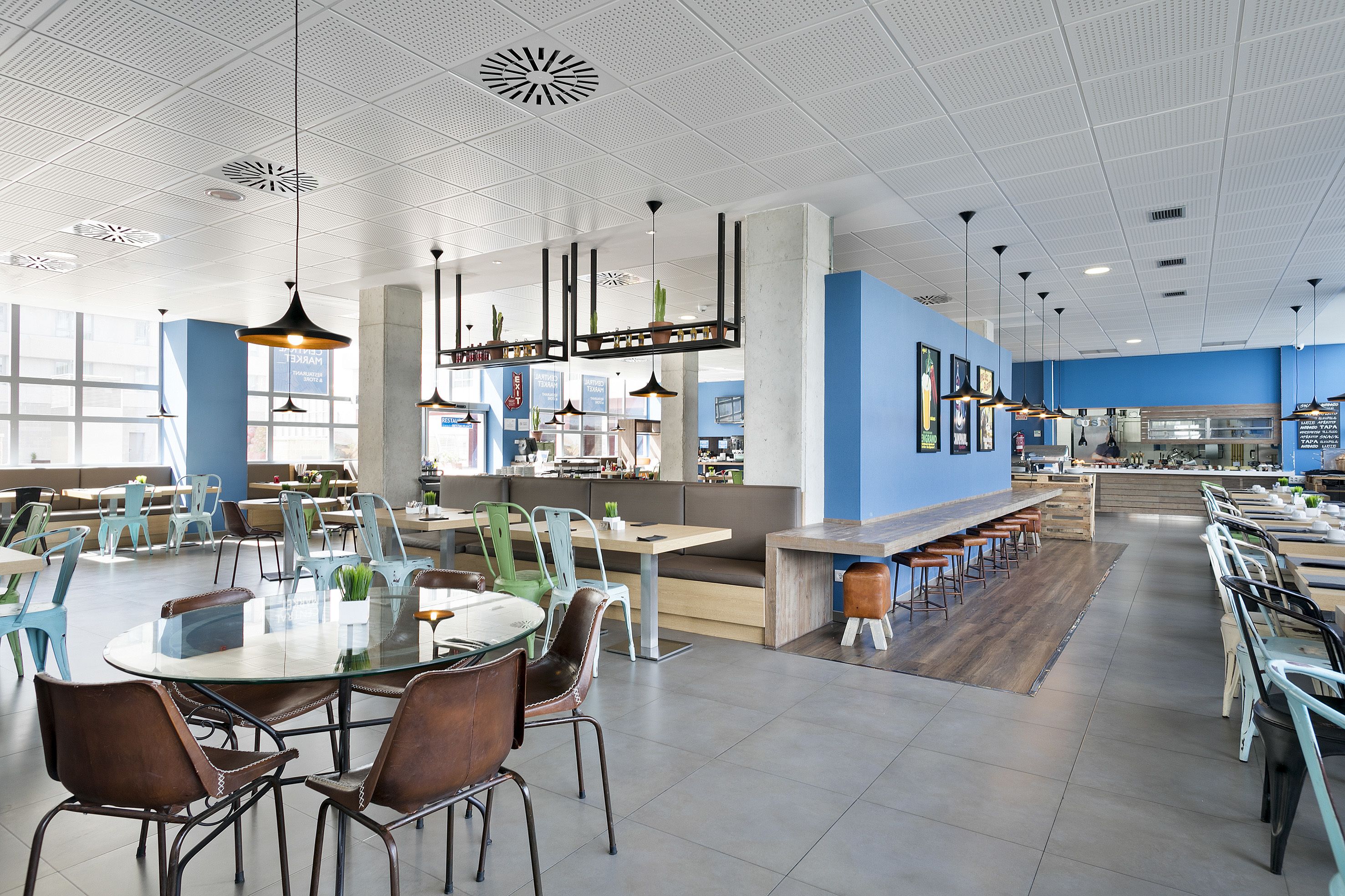A spacious restaurant with high ceilings, modern pendant lighting, and a mix of seating arrangements including tables and booths.