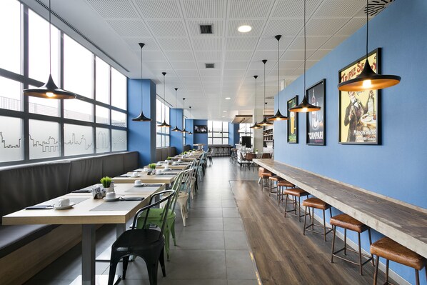 A modern restaurant with long communal tables, high ceilings, and large windows. - Madrid Airport Suites, Affiliated by Meliá (Madrid)