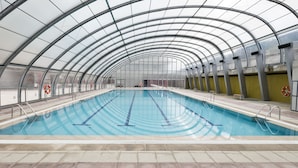 Una piscina interior con techo de vidrio y barandillas de metal.