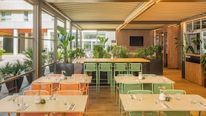 Un restaurante con mesas en el interior, una zona de bar y una recepción.