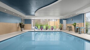Una piscina con sillas y plantas en macetas alrededor.