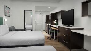 Una habitación de hotel moderna con una cama grande, un escritorio con computadora, un televisor y un armario.