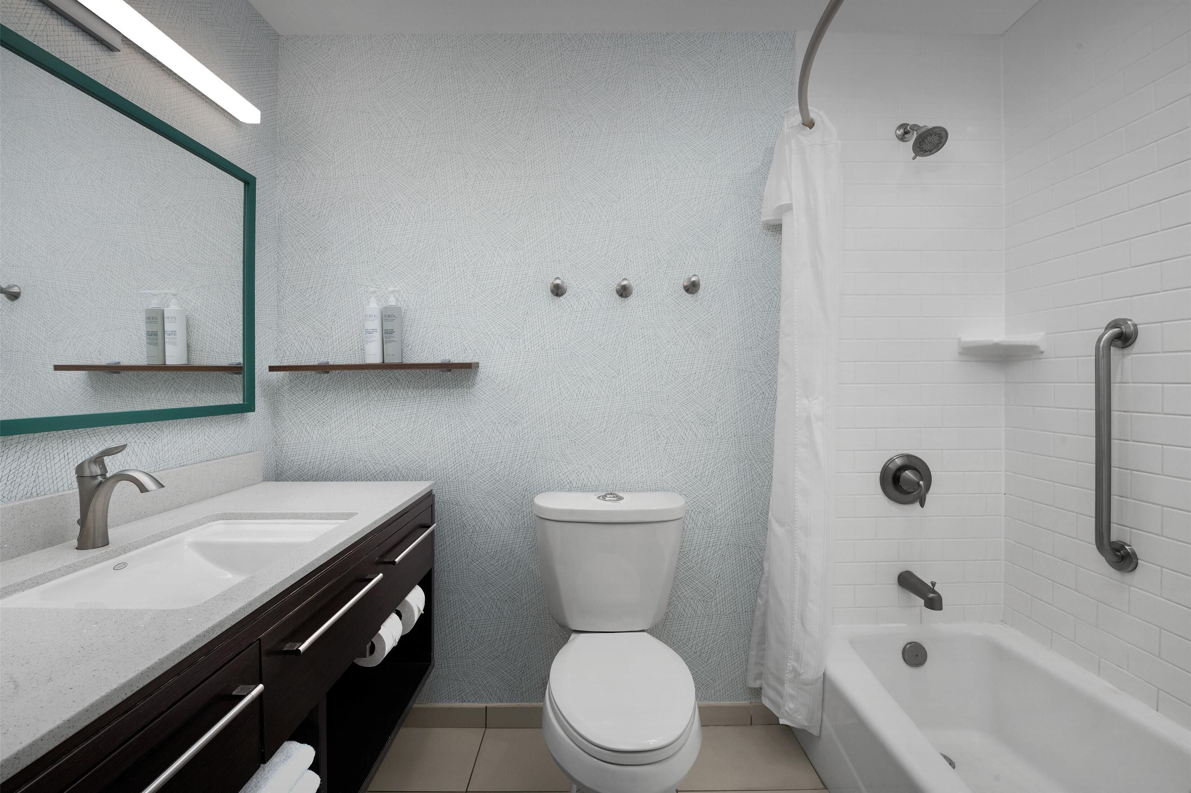 Un baño moderno con inodoro blanco, lavamanos con espejo y bañera.