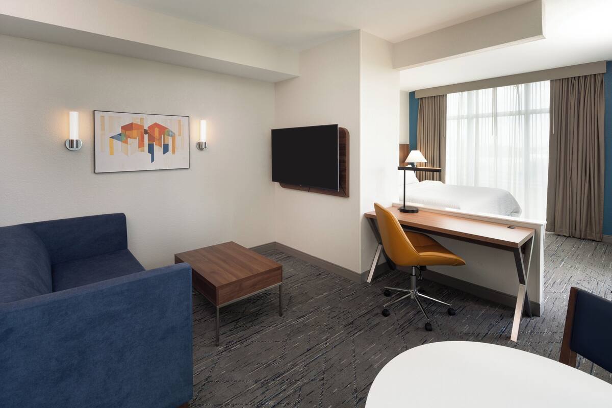 A hotel room with a bed, desk, chair, and a blue sofa.