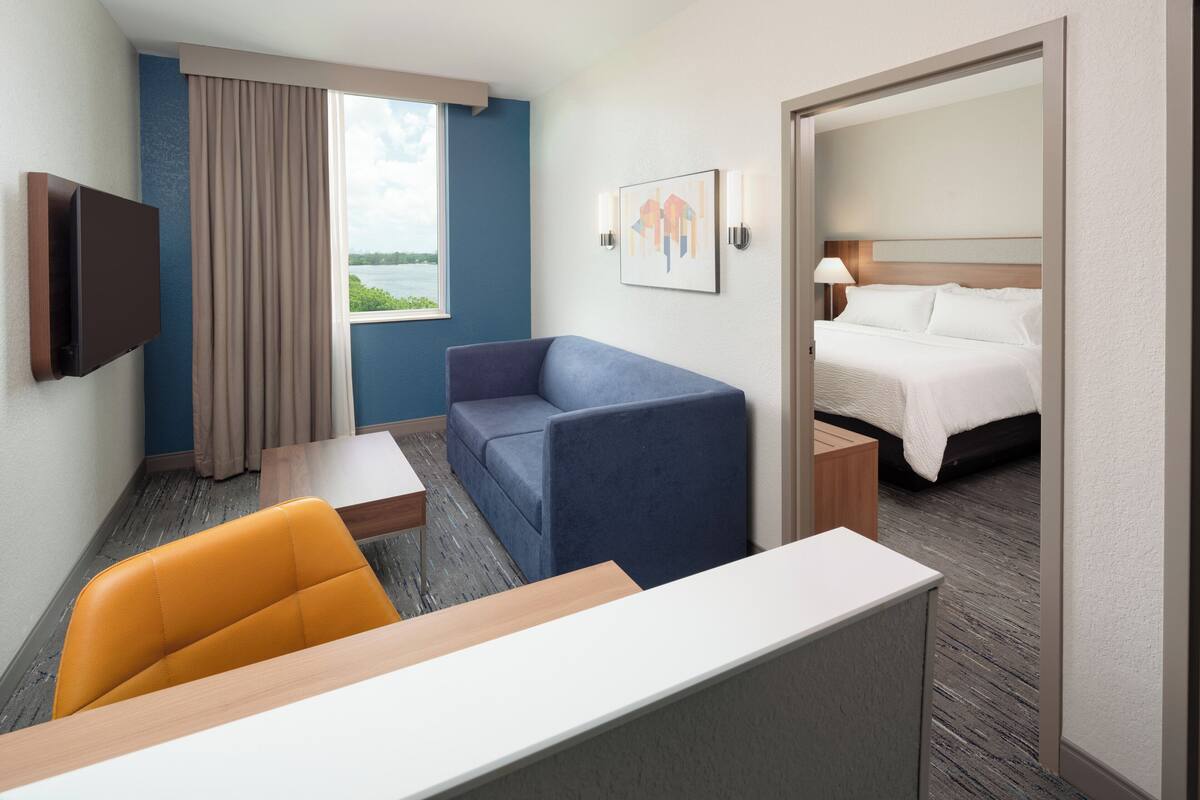 A hotel room with a bed, a sofa, a desk, and a TV.