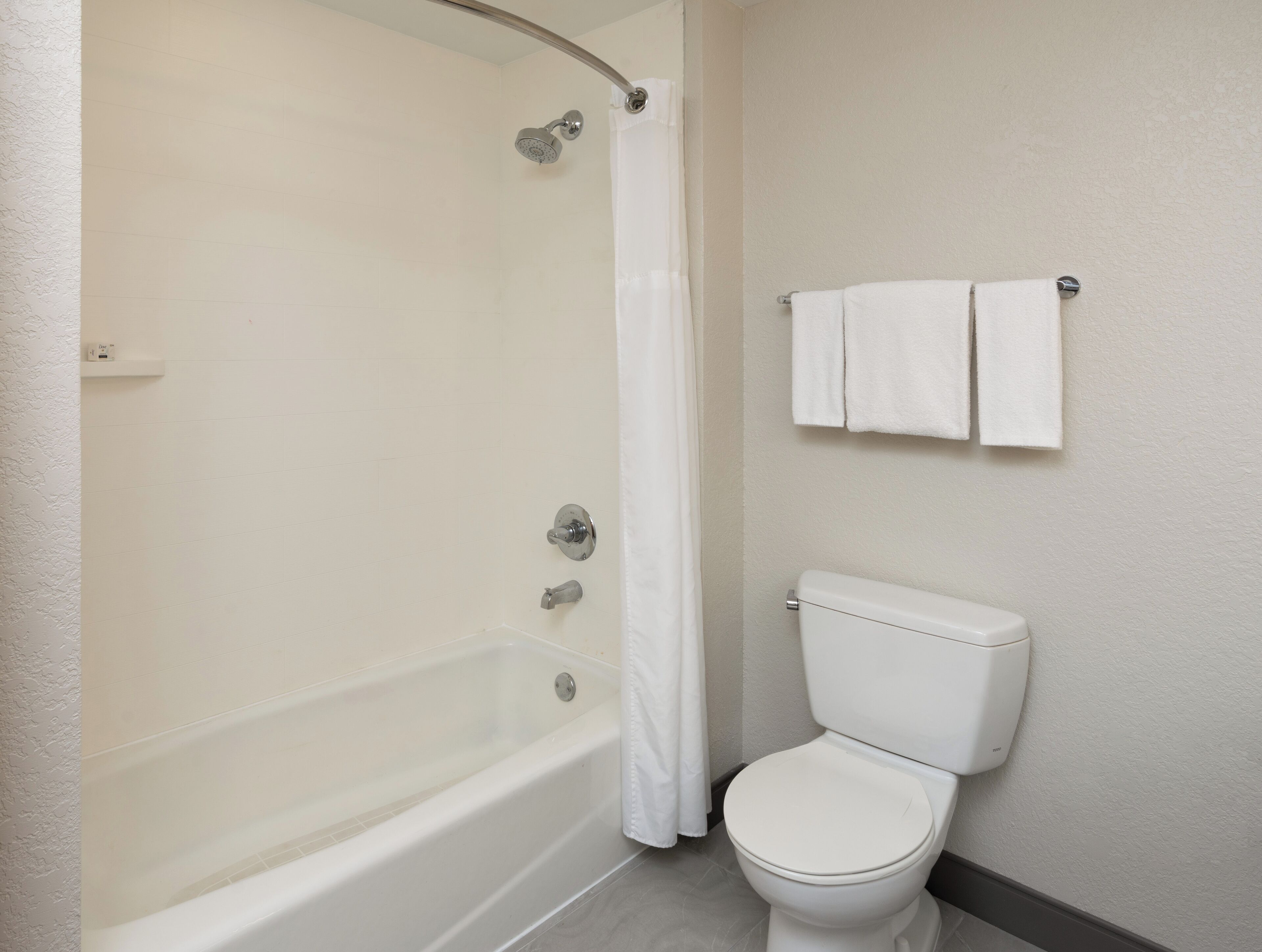 A bathroom with a bathtub, toilet, and a towel rack with two towels.