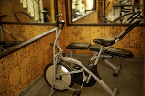 Un vélo d’appartement dans une salle de sport, avec un miroir sur le mur.