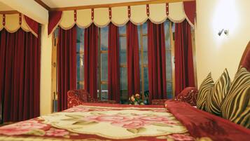 A bedroom with a large bed, red curtains, and a floral bedspread.