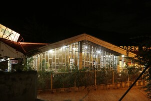 A modern building with large glass windows and a wooden facade at night.