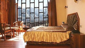 Un dormitorio con un ventanal grande, muebles de madera y una cama con colcha estampada.