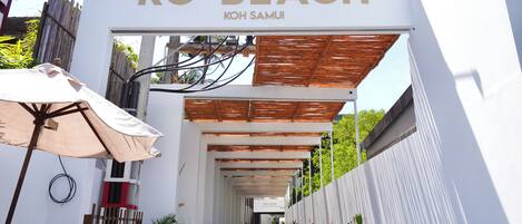 A pathway leading to a building with a sign reading 'KC BEACH KOH SAMUI'.