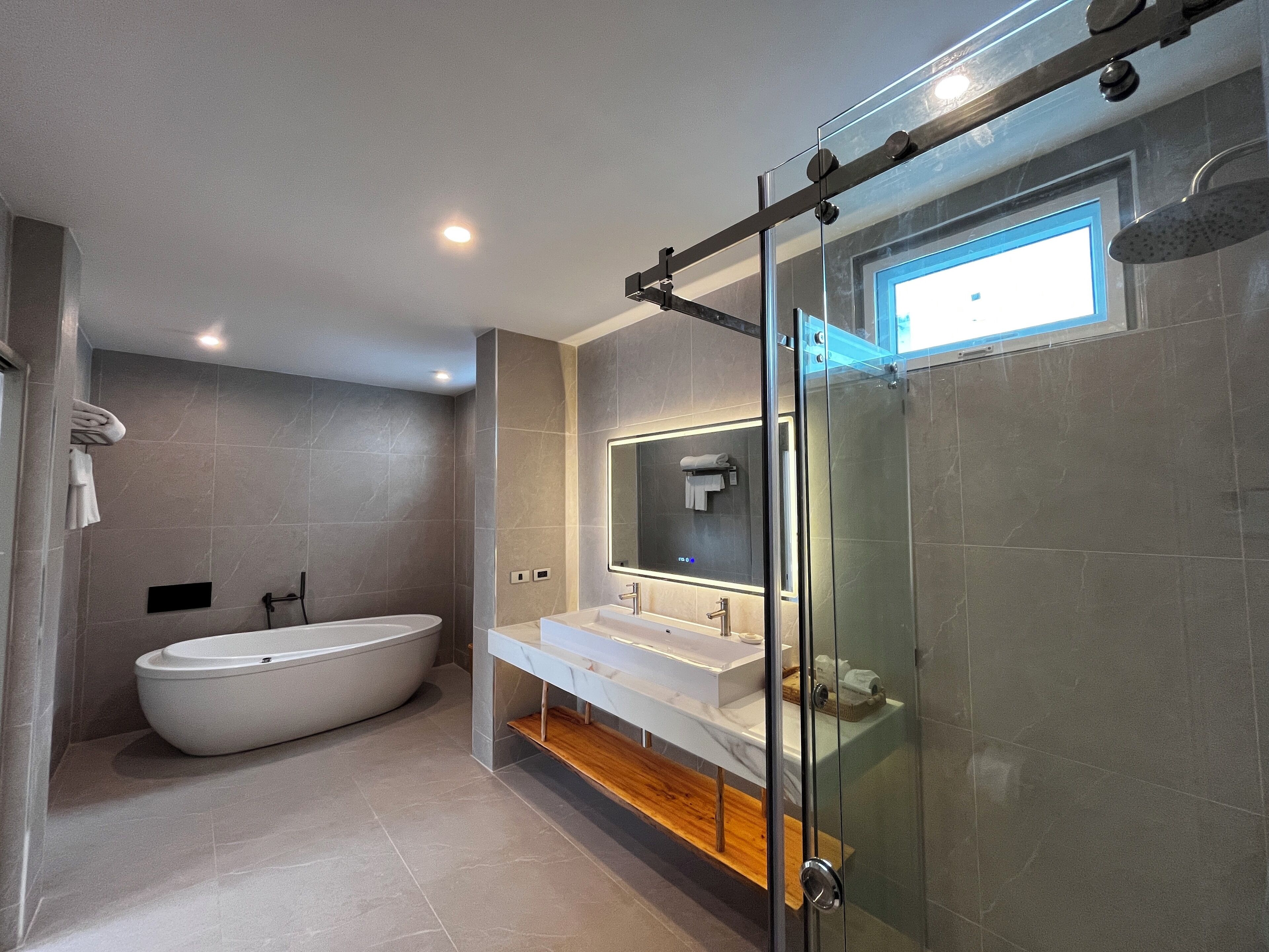 Un baño moderno con una bañera independiente, una ducha con mampara de vidrio y un tocador con espejo.