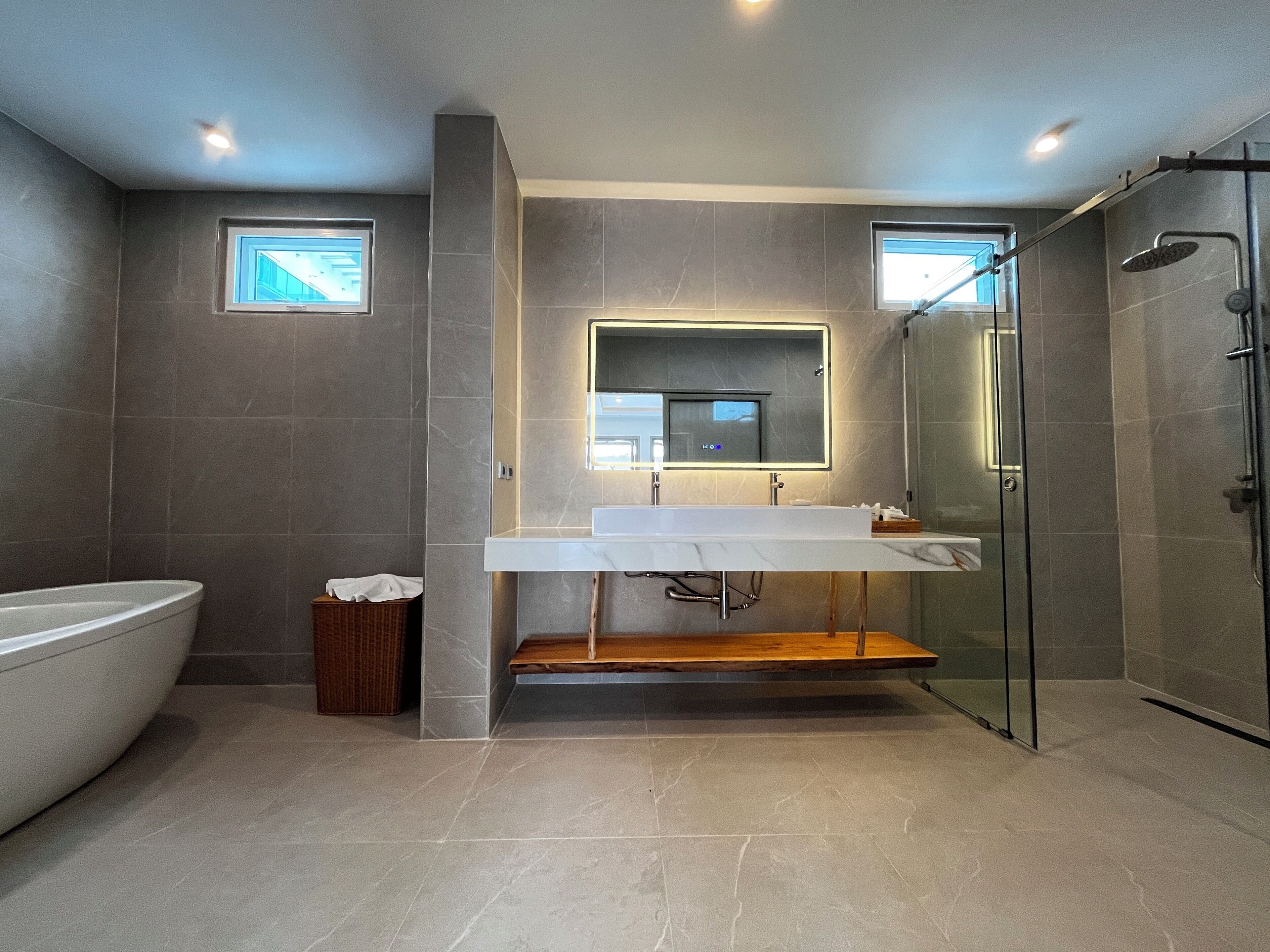 Un baño moderno con un espejo grande, una bañera y una ducha con paredes de vidrio.