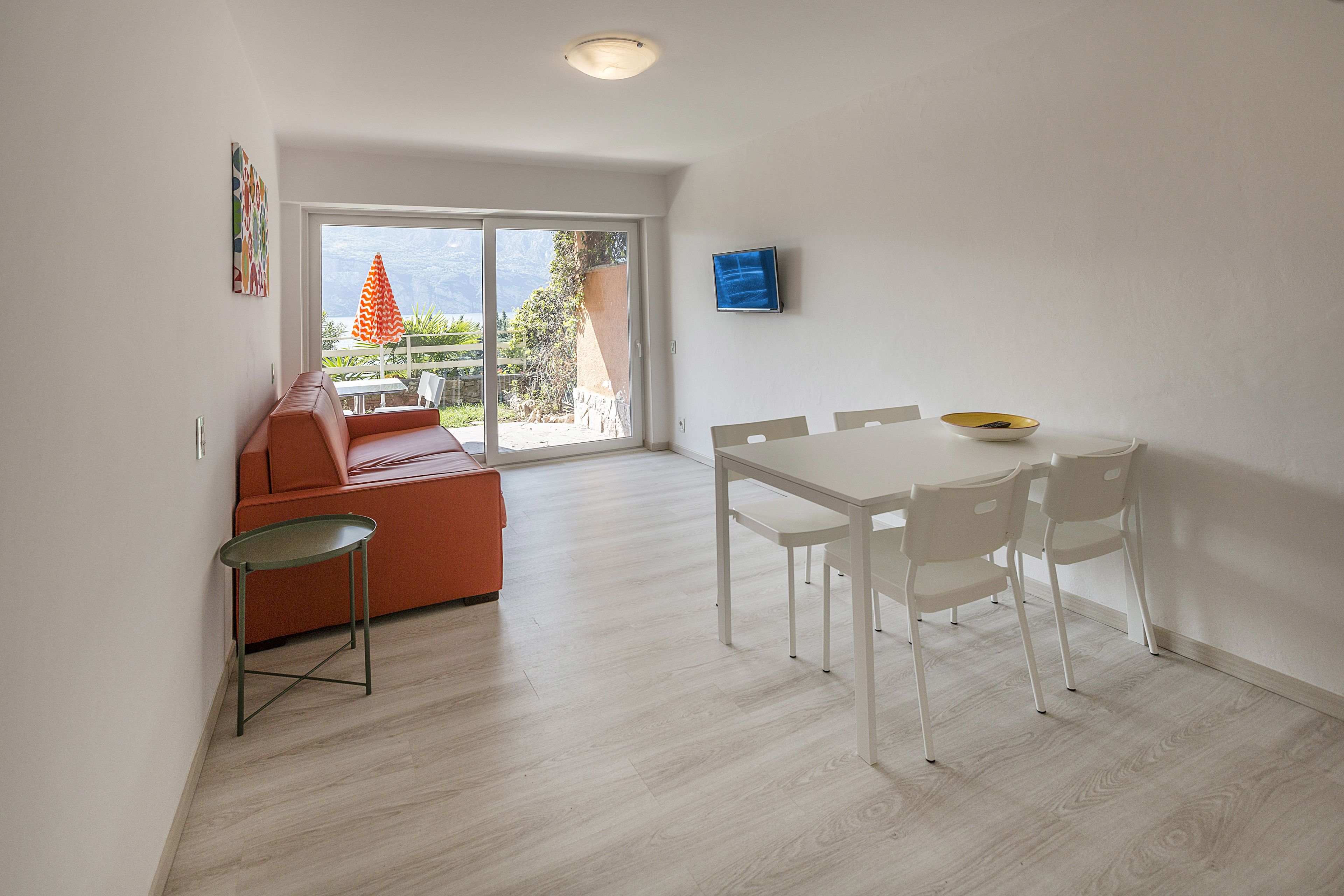 A modern living room with a sofa, a dining table with chairs, and a small table with a bowl.