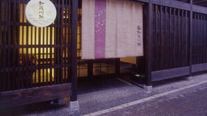 A traditional Japanese building with a wooden exterior and a sign with Japanese characters. - Kamogawa-kan Inn (Kyoto)