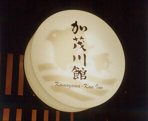 A circular sign with Japanese characters and the name "Kamogawa-Kan Inn" in English. - Kamogawa-kan Inn (Kyoto)