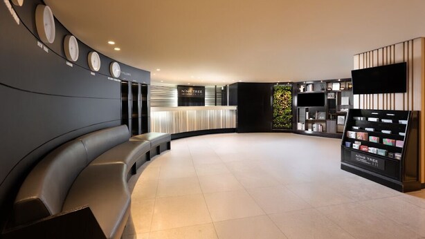 A modern lobby with a curved seating area, a reception desk, and a display of products. - NINE TREE BY PARNAS SEOUL MYEONDONG 1 (Seoul)