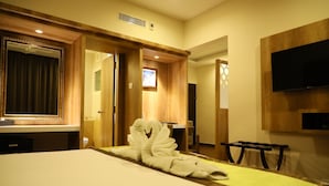 Una habitación de hotel con una cama, un televisor montado en la pared, una puerta de madera y un espejo.