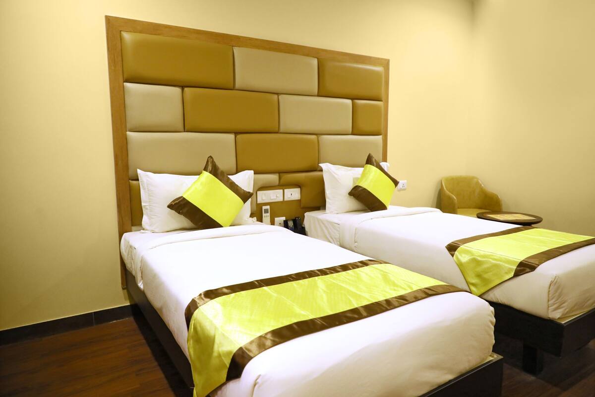 Una habitación de hotel con dos camas, un cabecero de madera y una mesita redonda.