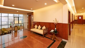 Un vestíbulo moderno con un sofá, sillas, una mesa de recepción y un amplio ventanal con vistas al exterior.