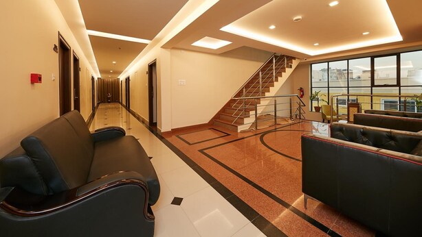 Vestíbulo de hotel con recepción, zona de estar y una escalera que sube a los pisos superiores.