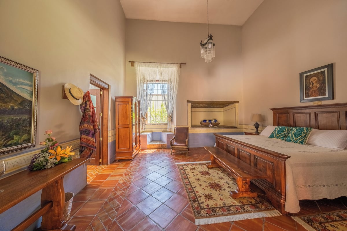 Un dormitorio con cama, muebles de madera, una araña y un cuadro en la pared.
