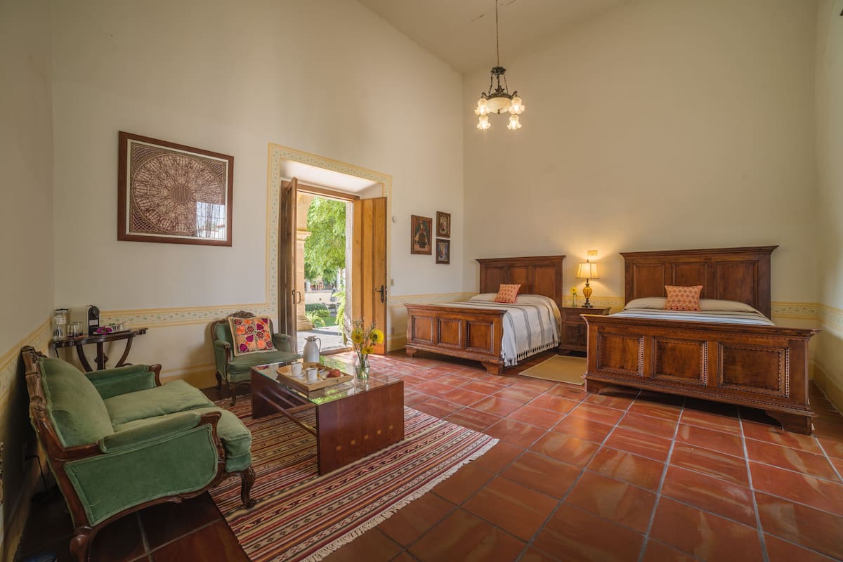 Una habitación tradicional con cama, sillón, mesa y candelabro.