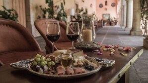 Una mesa dispuesta con una tabla de embutidos, copas de vino tinto y una vela.