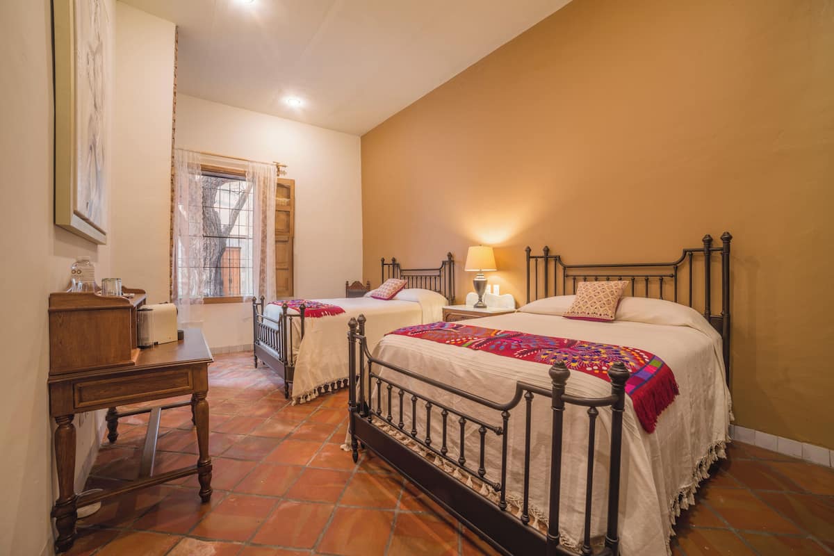 Un dormitorio con dos camas, una mesita de noche y una ventana con cortinas.