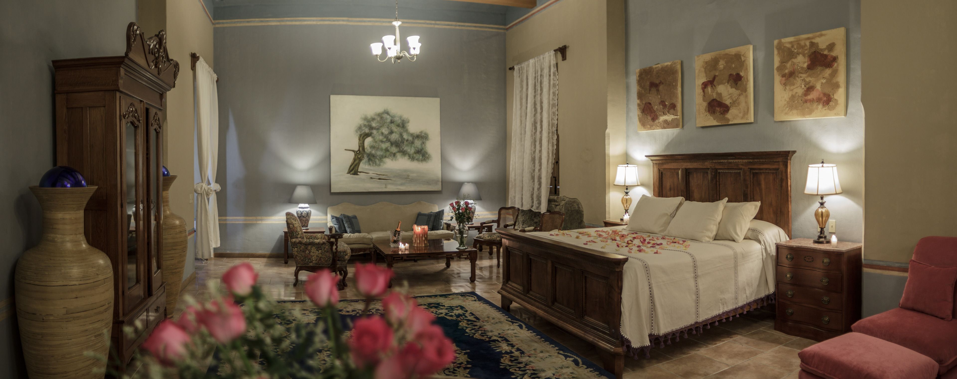 A traditional room with a bed, a sofa, a wooden cabinet, and a chandelier.