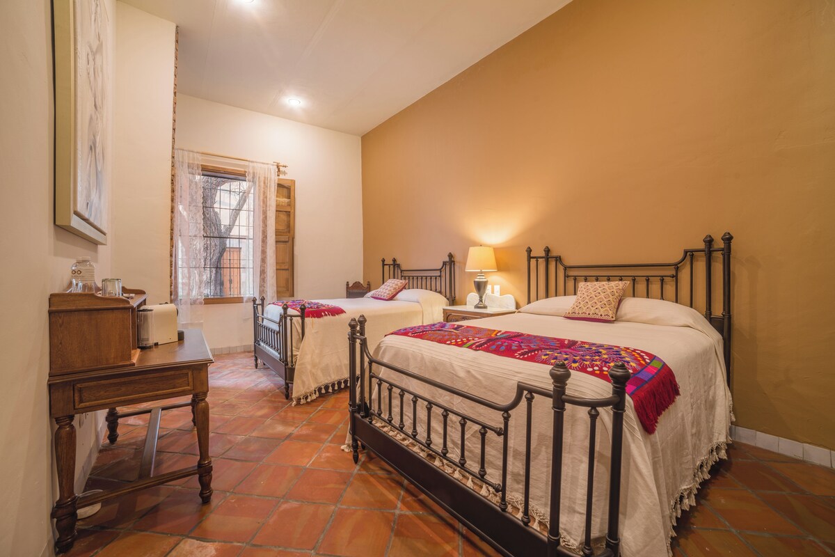 Une chambre avec deux lits, une table de chevet et une fenêtre avec des rideaux.