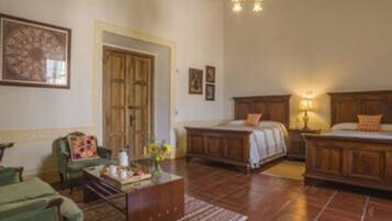 A room with a bed, a green armchair, a wooden dresser, and a painting on the wall.