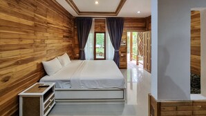A bedroom with wooden walls, a large bed, a bedside table, and a view of the outdoors through a window. - Phuvara Boutique (Krabi)