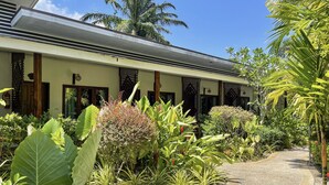 A modern building with a covered walkway, surrounded by lush tropical plants and palm trees. - Phuvara Boutique (Krabi)