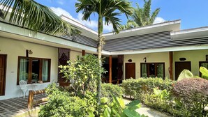 A modern building with a covered outdoor area, featuring a palm tree and various plants. - Phuvara Boutique (Krabi)