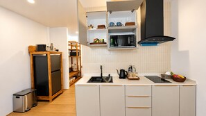 A compact kitchen with a built-in microwave, a black range hood, and a stainless steel refrigerator. -  Kirivara Suite & Wellness (Krabi)