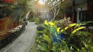 A pathway flanked by lush greenery and a building with a sloped roof. - Phuvara Boutique (Krabi)