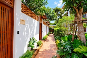 A pathway flanked by white walls and wooden doors, leading to a covered area with a tiled roof. -  Kirivara Suite & Wellness (Krabi)