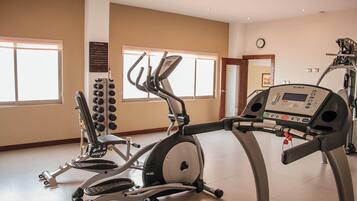 Un gimnasio con equipo de cardio, incluyendo cintas de correr y una máquina elíptica.