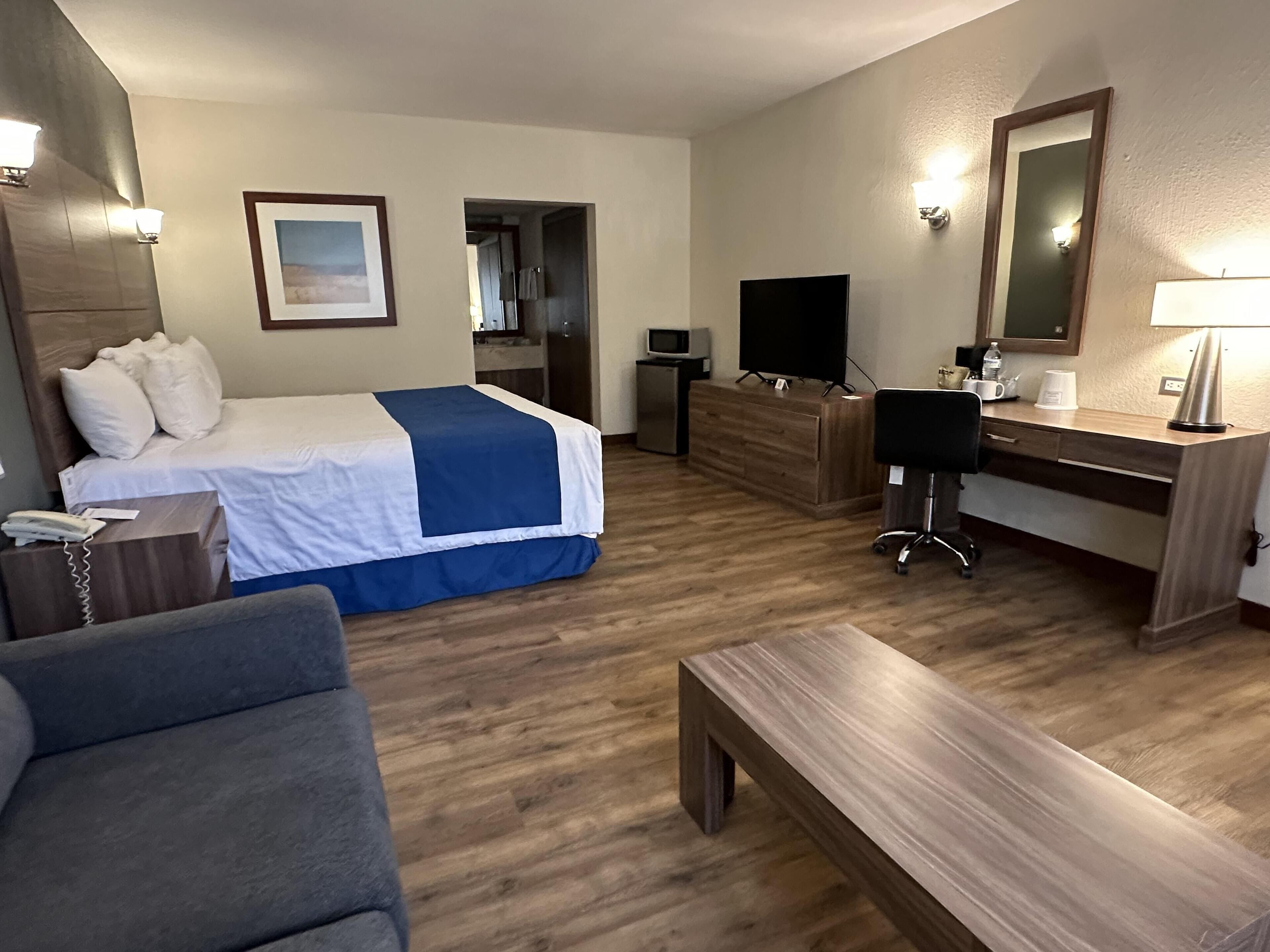 Una camera d'albergo con un letto, una scrivania, una sedia e una televisione.