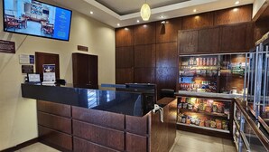 Een receptiegedeelte met een houten receptiebalie, een aan de muur bevestigde televisie en een vitrine voor snacks.