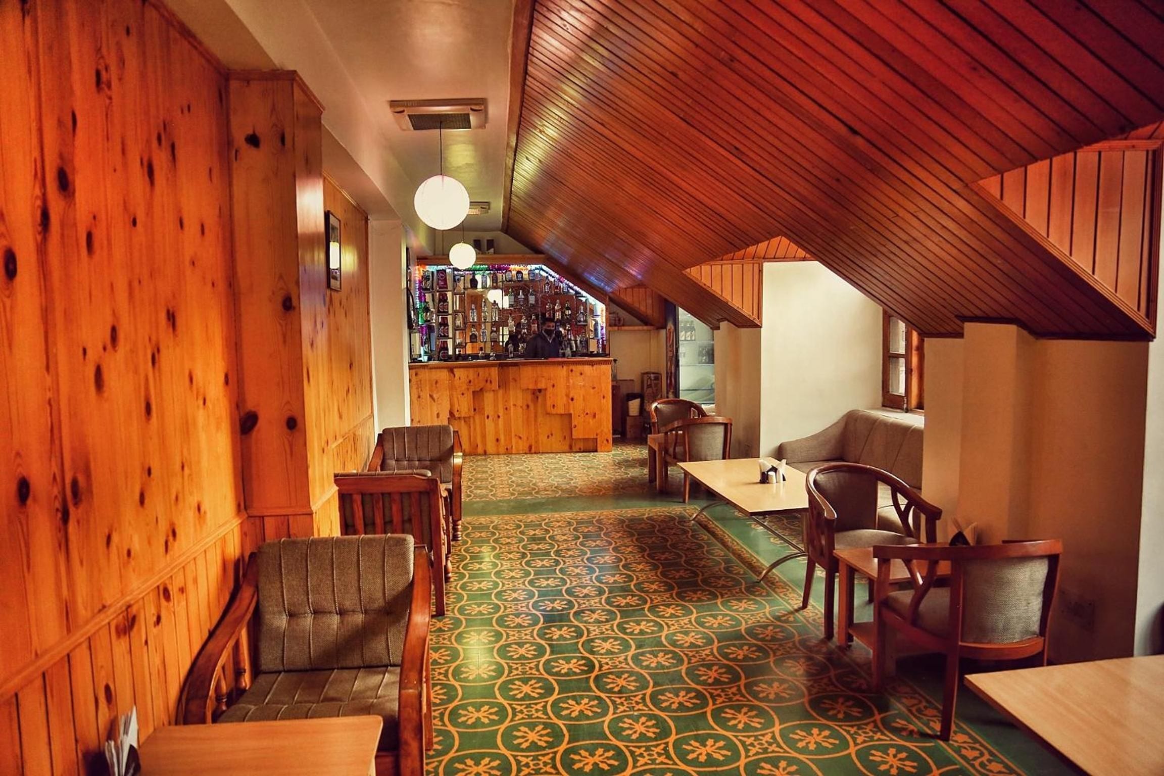 Un intérieur chaleureux avec des murs en bois et un sol à motifs, comprenant un espace bar et des sièges.