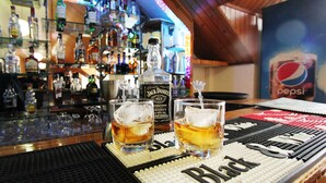 Een bar met twee glaasjes whiskey, een fles Jack Daniel's en een Pepsi reclamebord op de achtergrond.