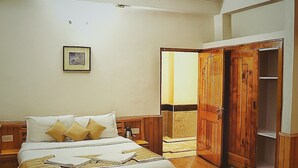 Een slaapkamer met een bed, een houten garderobe, een plafondventilator en een ingelijst schilderij aan de muur.