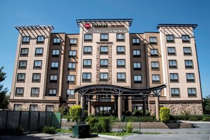 Un hotel de varios pisos con una entrada central, varios balcones y un cielo despejado.